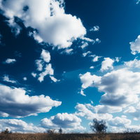 青空と白い雲が浮かぶ原っぱの風景、昼間の晴天の屋外景観の写真