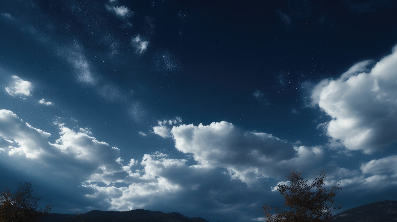雲の合間から輝く星々を見上げる夜空の風景