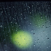 雨が降った窓ガラスに流れる水滴と青からオレンジ色のグラデーション背景の写真