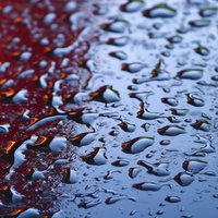 赤と青の鉄板に落ちる水滴のマクロテクスチャーの写真