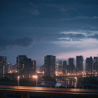 天気が崩れはじめた夕暮れの都会ビル群と街灯の写真