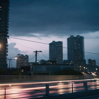 夕暮れの都会を走る光跡と高層マンションの写真