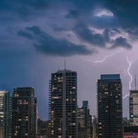 雷雲がビル群に落ちる落雷と夜景、都会の夜間の天候表現の写真