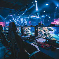 青とピンクのライティングが施されたeスポーツ施設のゲーミング環境の写真