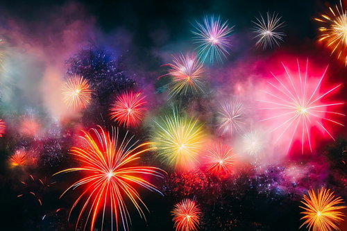 夜空に打ち上がる色とりどりの花火が光の粒子とともに広がる