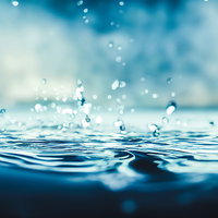 青い水面に落ちる透明な水滴と波紋が広がる瞬間の写真