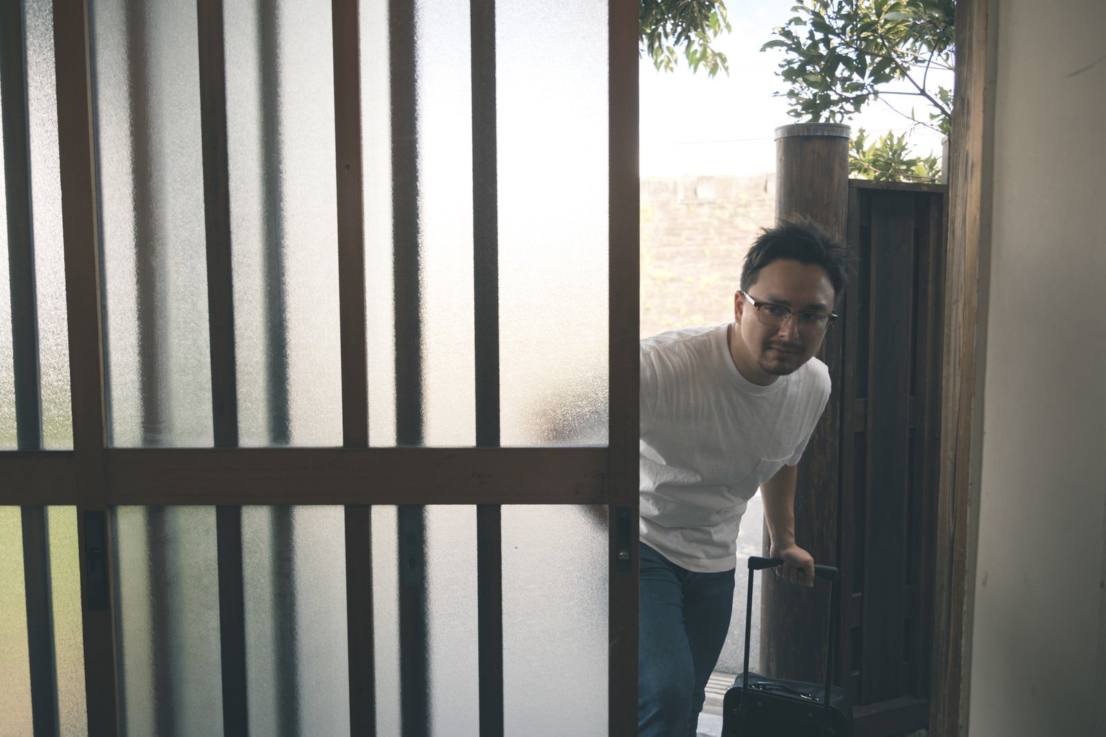 古民家の玄関で木製の引き戸を開けようとしている男性［モデル：Max_Ezaki］