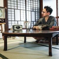 アナログテレビがある和室で甚平を着てくつろぐ外国人観光客の写真