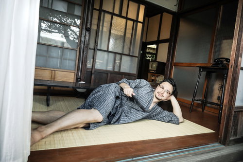 古民家の縁側で横になってくつろぐ外国人男性