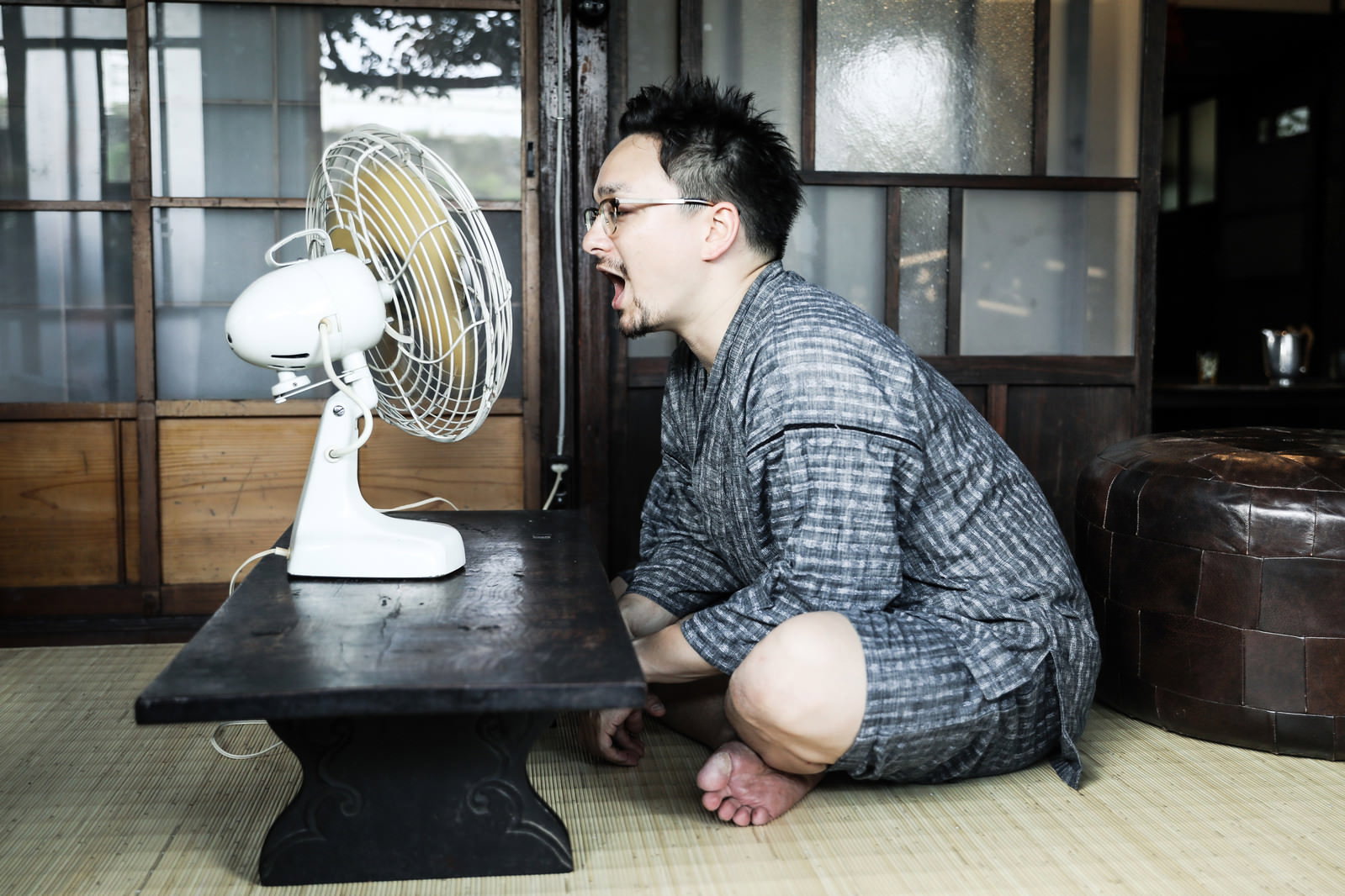 古民家の室内でレトロな扇風機の前で風を浴びる外国人男性［モデル：Max_Ezaki］