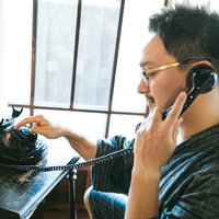 ダイヤル式電話機を使って電話をかけるドイツ人ハーフの写真