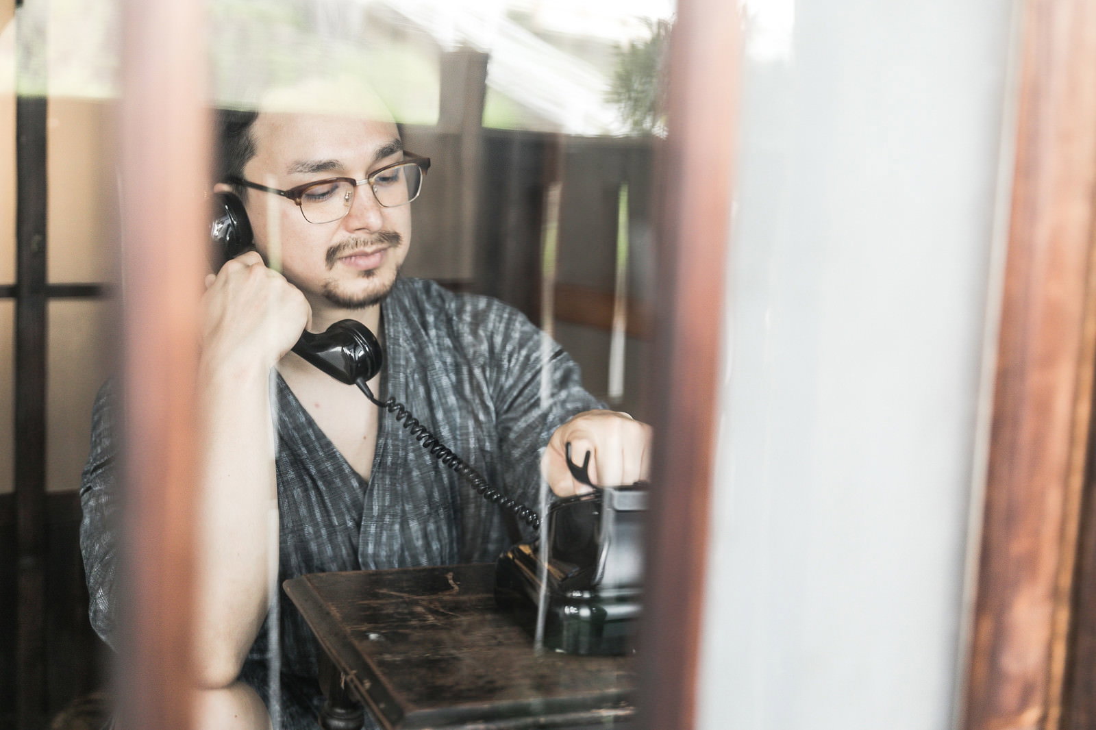 黒い受話器を耳に当てて通話している外国人男性［モデル：Max_Ezaki］
