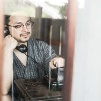 黒電話を使って通話する外国人男性のレトロなの写真