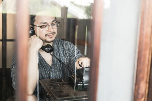 黒電話を使って通話する外国人男性のレトロな