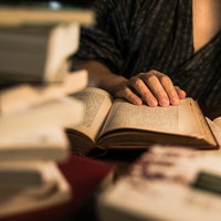 積まれた本の中で徹夜して調べものをする手元の写真