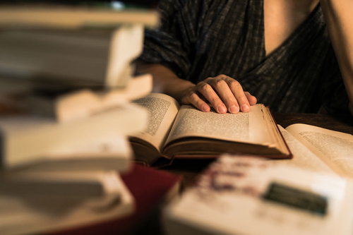 積まれた本の中で徹夜して調べものをする手元