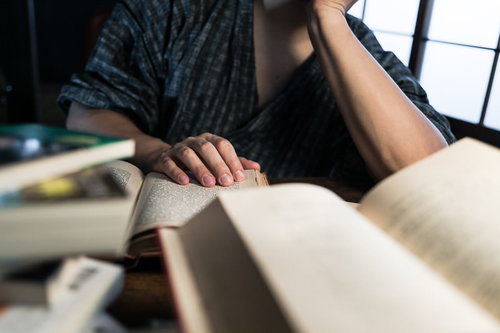書斎の机で複数の文献を読みあさる学習風景
