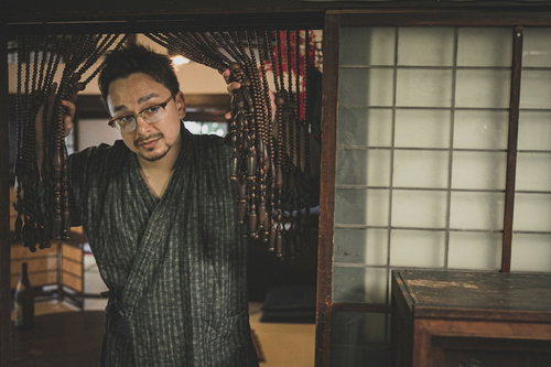 古民家の玄関に立つ甚平姿の外国人男性とじゃらじゃらのれん