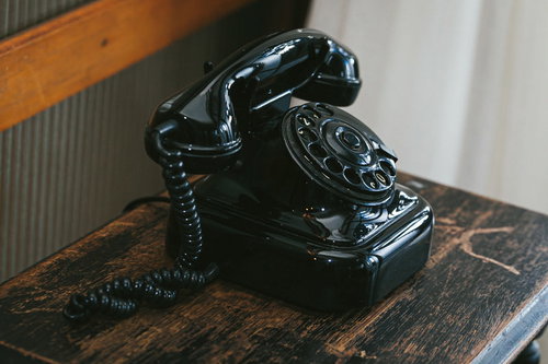 木製テーブルに置かれた昔なつかしい黒電話