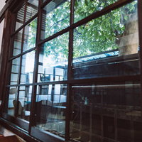 古民家の和室のガラス窓から見える庭の木漏れ日の写真
