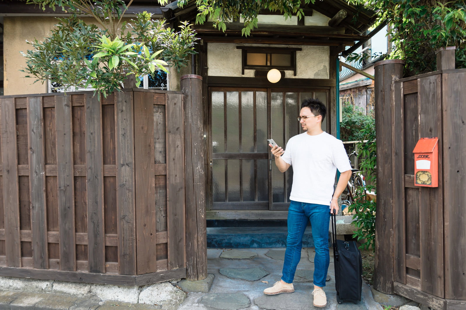 古民家の軒先でスマートフォンを操作する外国人観光客の男性［モデル：Max_Ezaki］