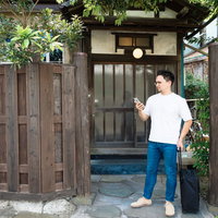 古民家の軒先で予約を確認する外国人観光客の写真