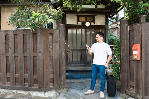 古民家の軒先で予約を確認する外国人観光客