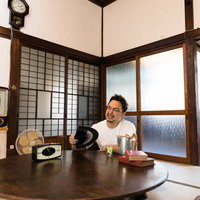 日本の夏は暑いと古民家で扇子を使う外国人観光客の写真