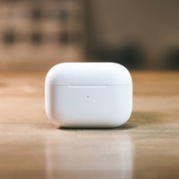 木製テーブルに置かれた白いAirPodsケースの写真