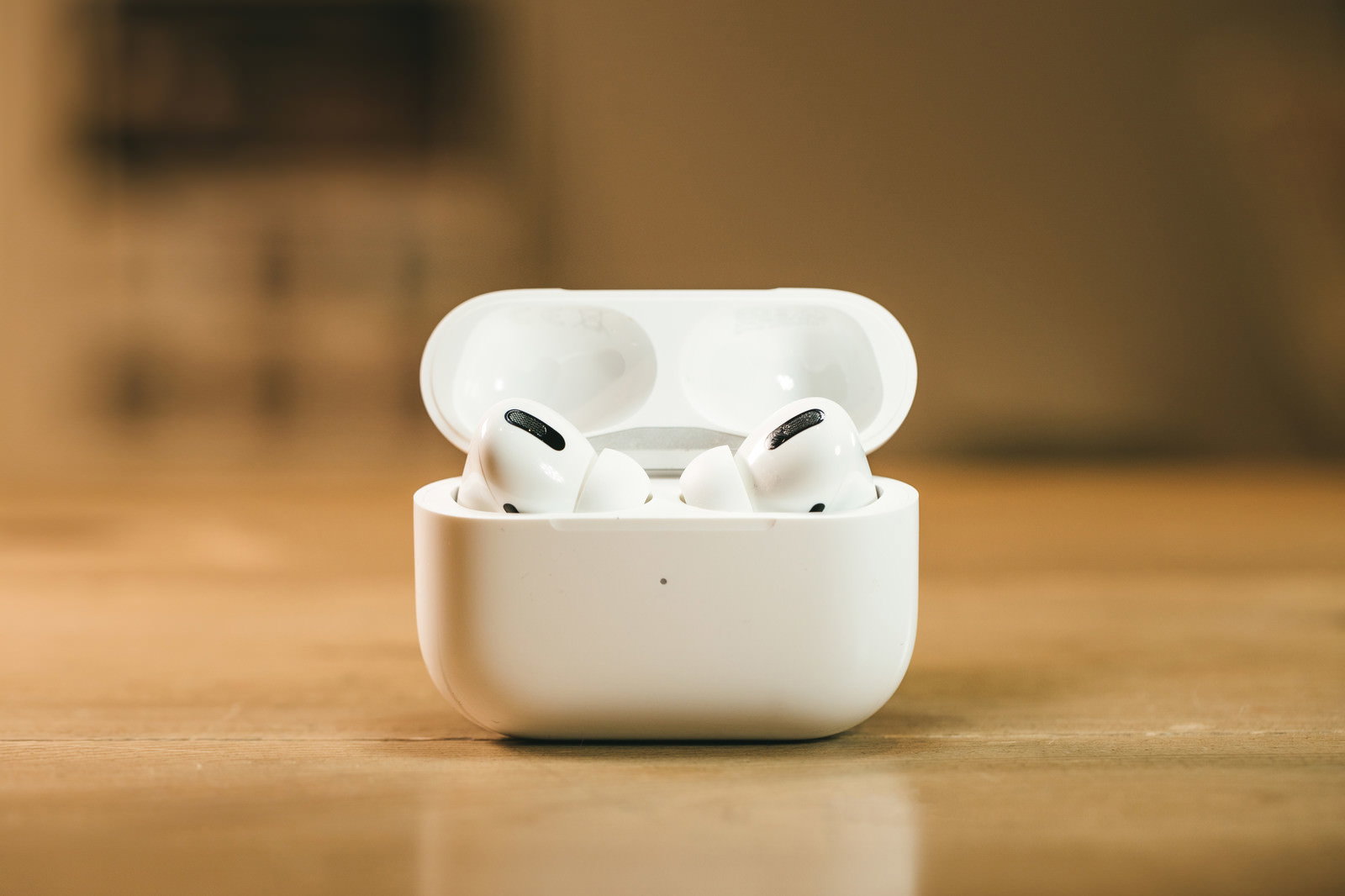 木製テーブルの上に置かれた白いAirPods Proの充電ケース