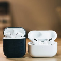 白いAirPods Proと黒いケースのAirPods、卓上に並べて配置の写真