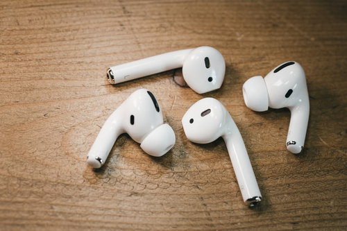 木目のテーブルに散らばるAirPodsとAirPods Proの充電ケース