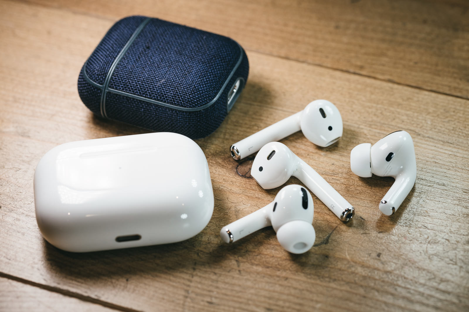 木目調の机の上に置かれた白いワイヤレスイヤホンと充電ケース