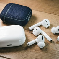 卓上の木目机に置いたワイヤレスイヤホンと充電ケースの写真