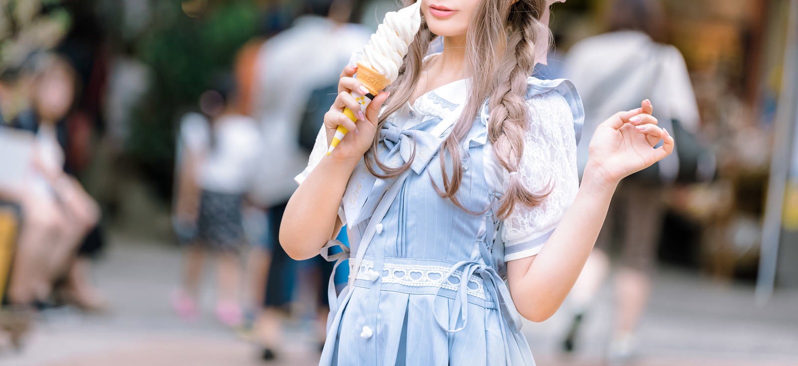 デニムのオーバーオールを着た女性がソフトクリームを持っている［モデル：石投げて美奈代］