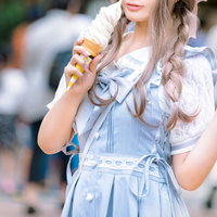 デニムのオーバーオールを着た三編みの髪の女性がソフトクリームを食べるの写真