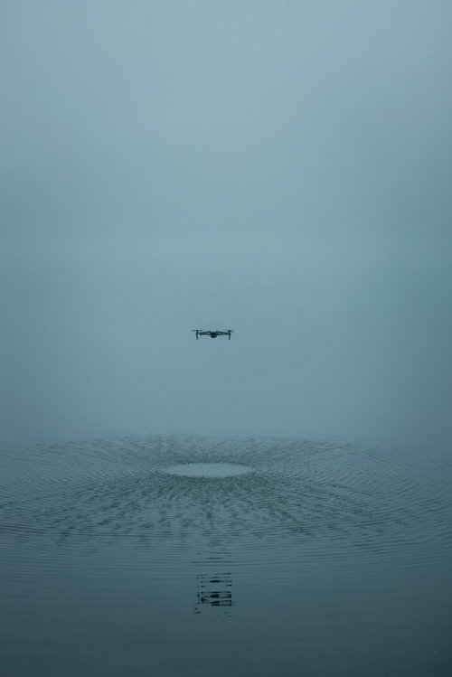 水上で浮遊するドローンと水面への反射、霧の悪天候での飛行