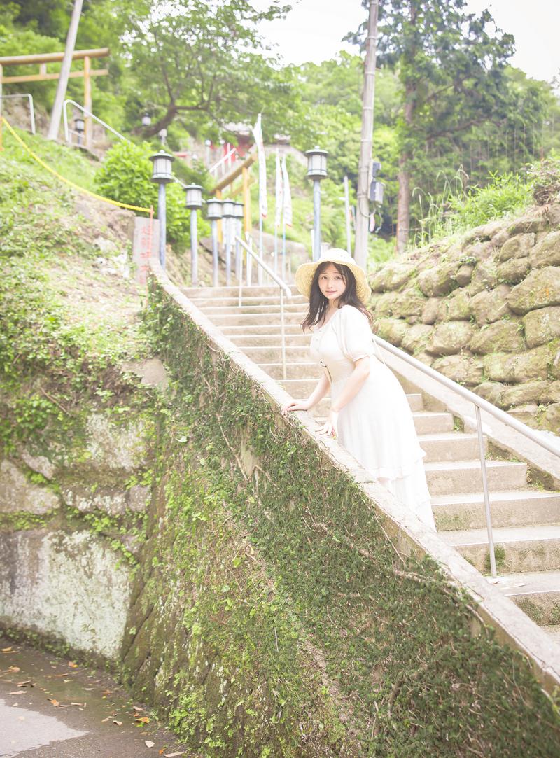 苔むした石垣に囲まれた階段を上る、白いワンピース姿の女性［モデル：茜さや］