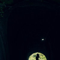 トンネルと女性のシルエット｜緑に包まれた切通しの散策路の写真