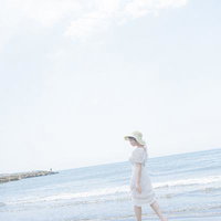 岩井海水浴場の波打ち際を歩く麦わら帽子姿の女性の写真