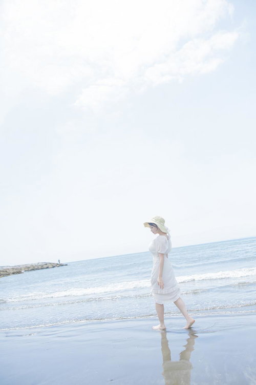 岩井海水浴場の波打ち際を歩く麦わら帽子姿の女性