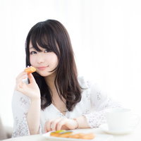 エクレア、お先に食べちゃうね。白い服の女性がスイーツを頬張るの写真