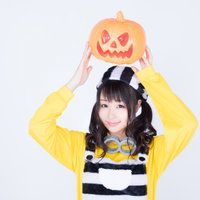 ハロウィンのかぼちゃお化けを両手で持ち上げる仮装女子の写真