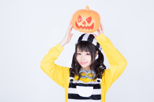ハロウィンのかぼちゃお化けを両手で持ち上げる仮装女子