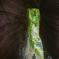高さ10mもある燈籠坂大師の切通しトンネルを見上げる女性の写真