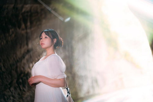 燈籠坂大師の切通しトンネルから差し込む光を浴びる観光女性