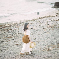 沖ノ島の砂浜を歩く麦わら帽子姿の女性ポートレートの写真