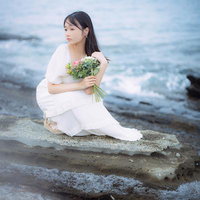 沖ノ島の北の岩礁で花束を持ち海を背に佇む女性のポートレートの写真