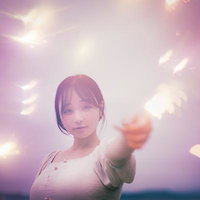 手持ち花火の煌めきを楽しむ白い服の女性の夏の夜の写真