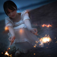 砂浜で手持ち花火を楽しむ女性の写真